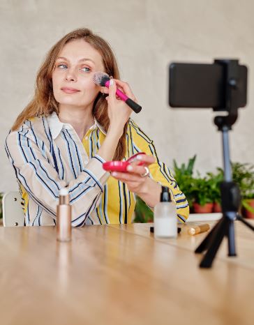 Woman filming herself while putting blush on